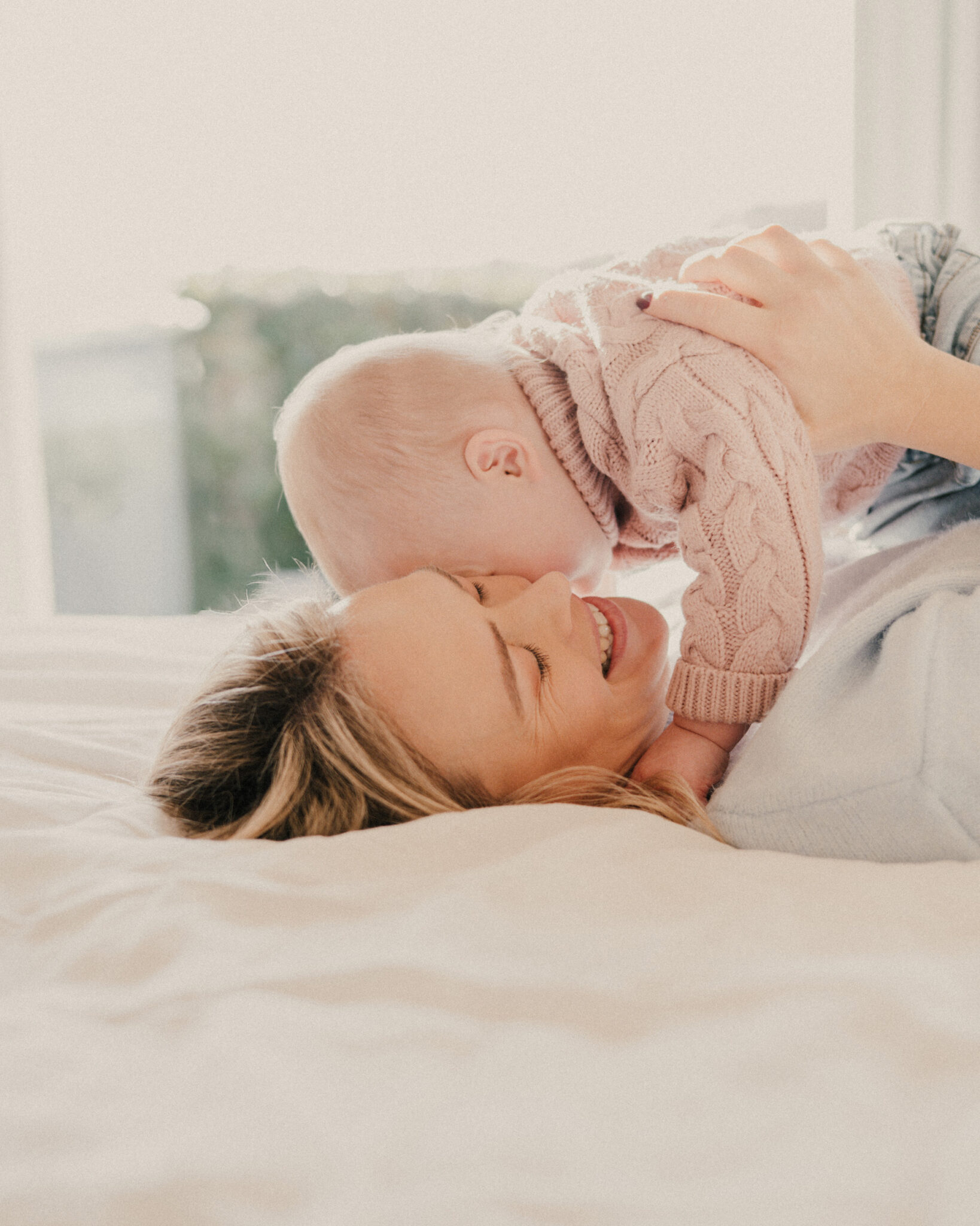 Mother laying on her back with her baby's face against her cheek.