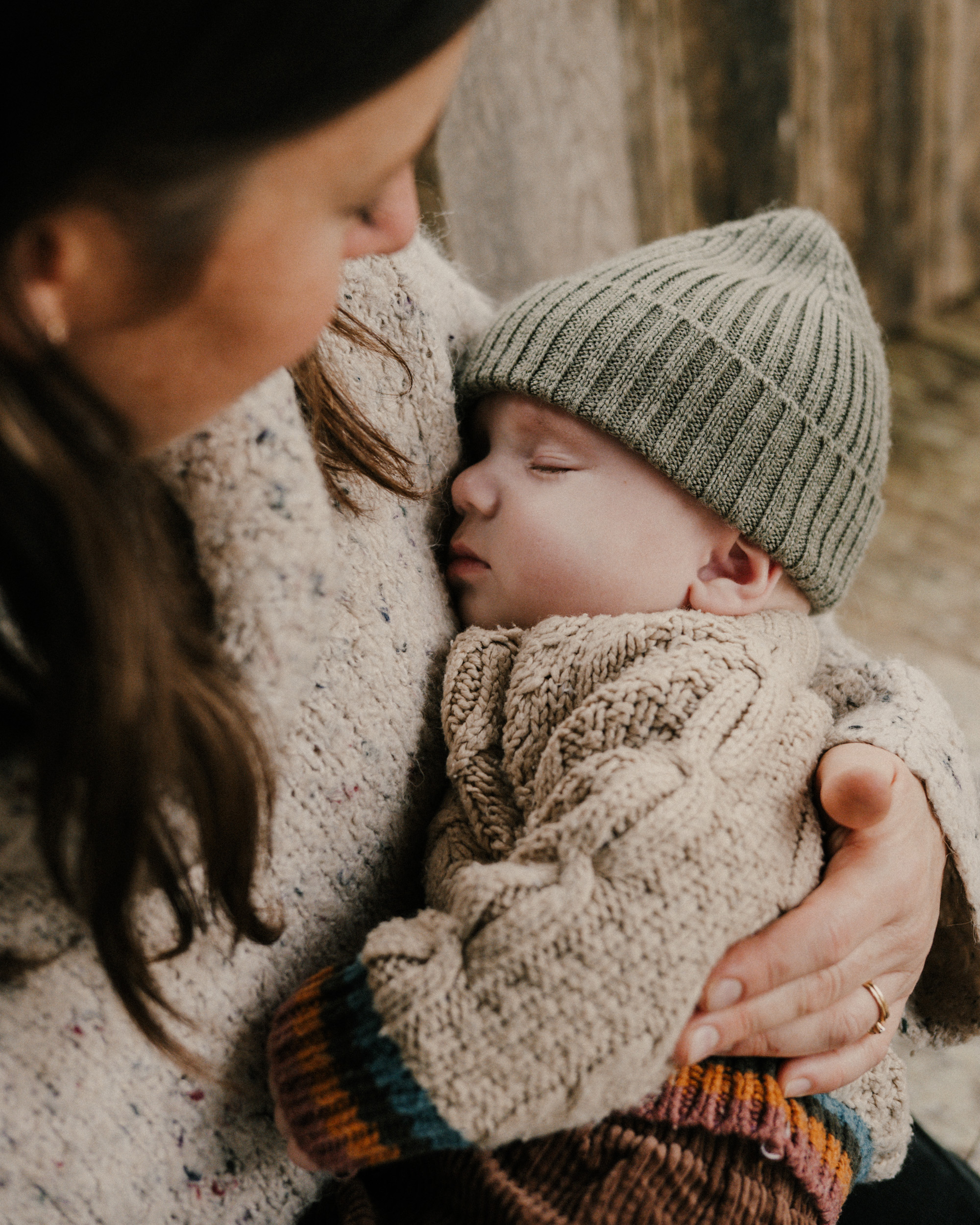 Mother holding sleeping infant in her arms as he sleeps.