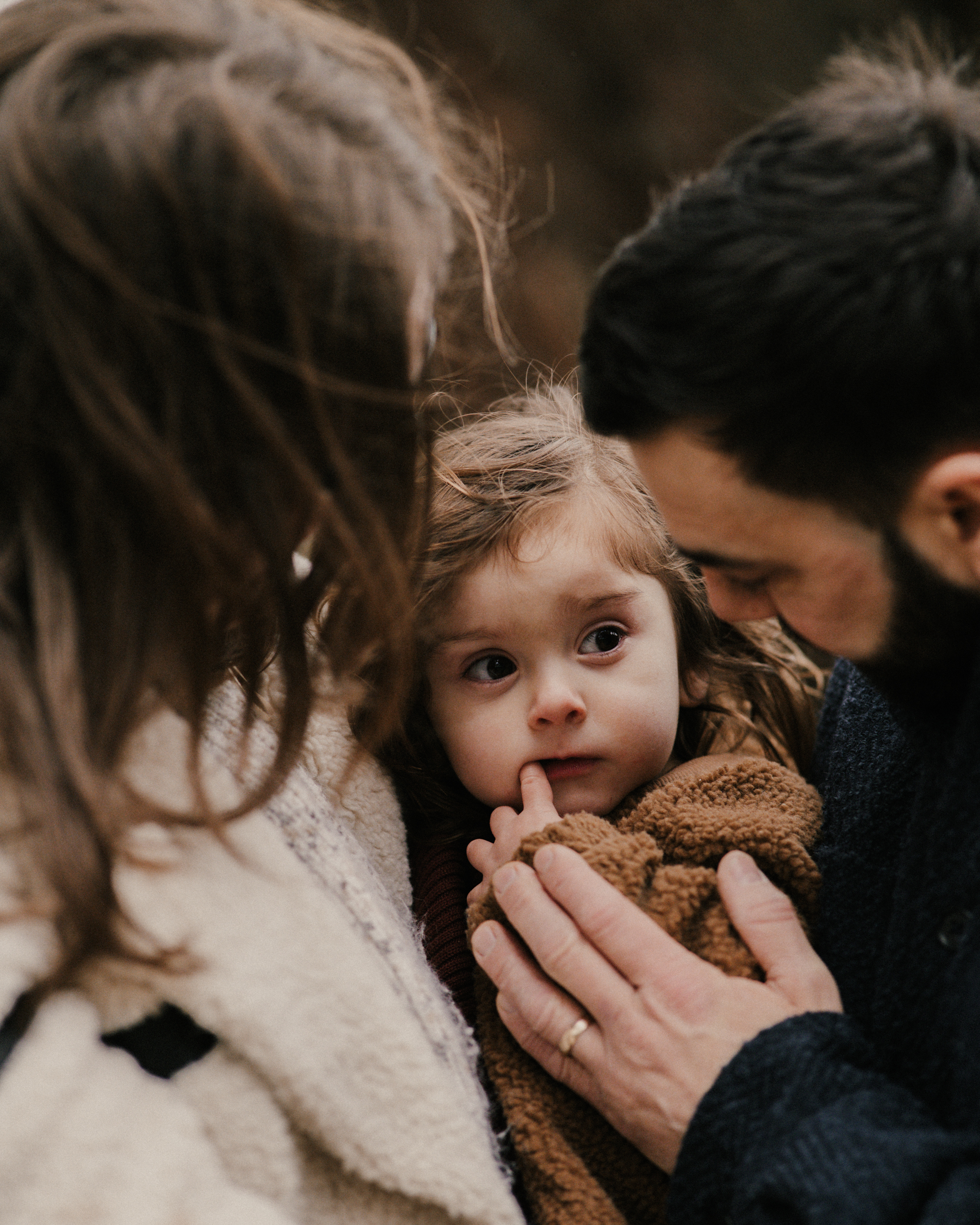 Parents lovingly looking at toddler, fathers hand placed upon toddlers arm.