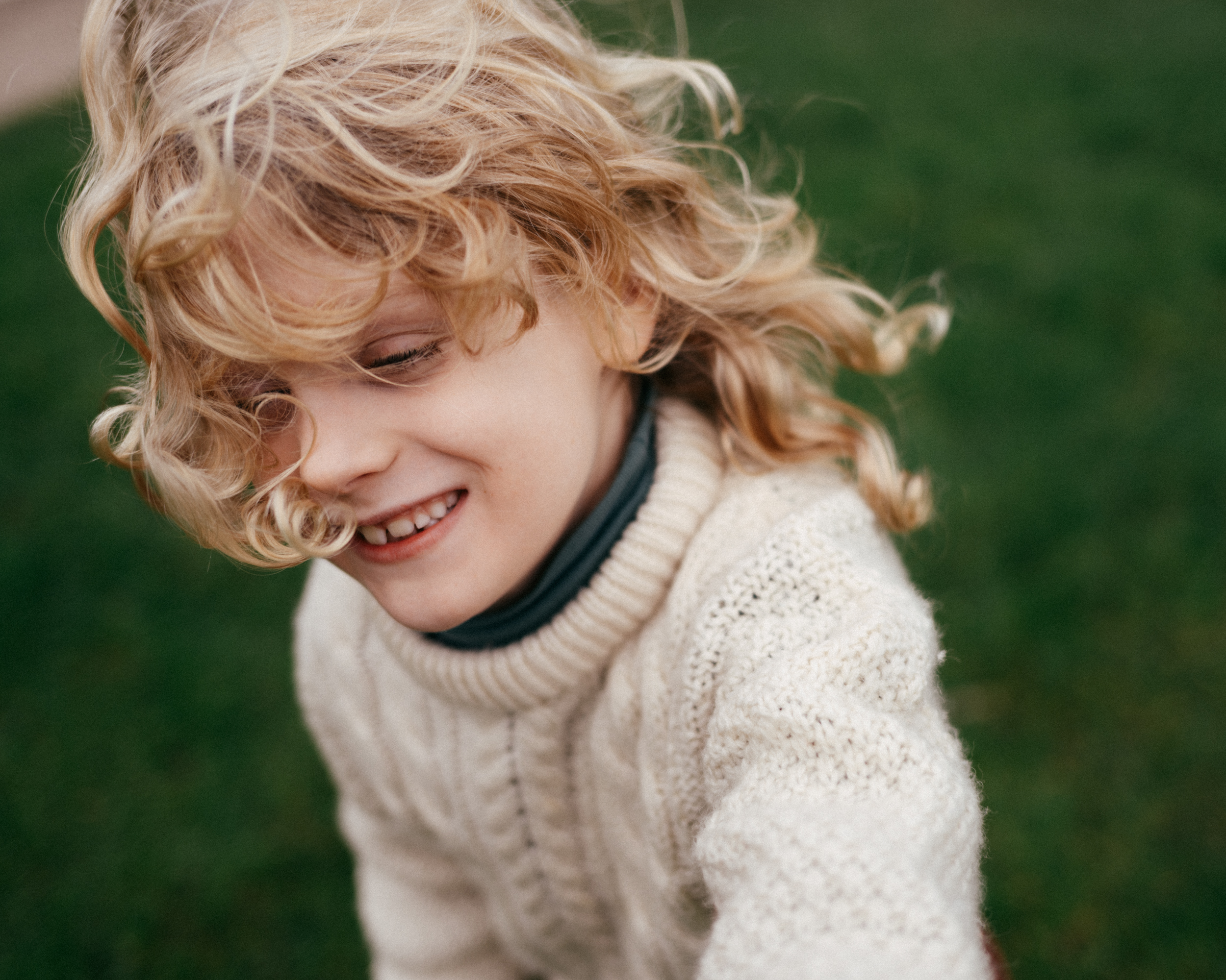 Young child laughing and running with wind blowing long hair.