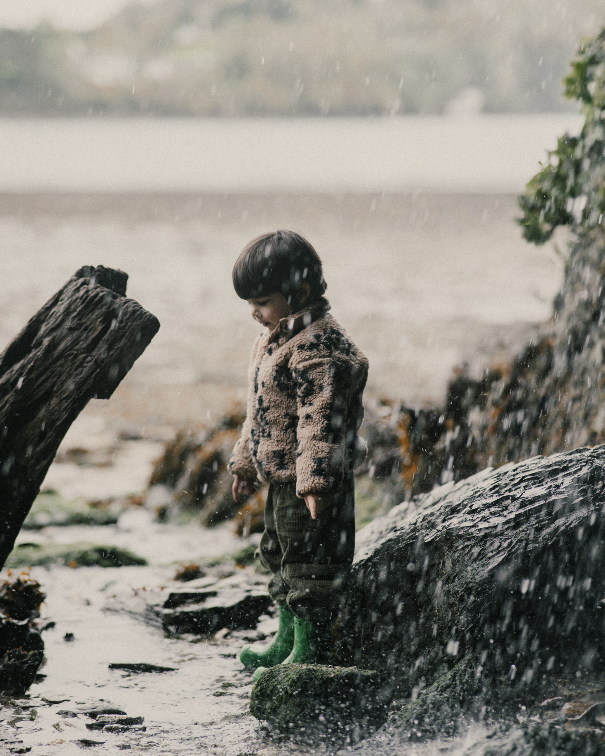Young boy standing in spray from a waterfall.