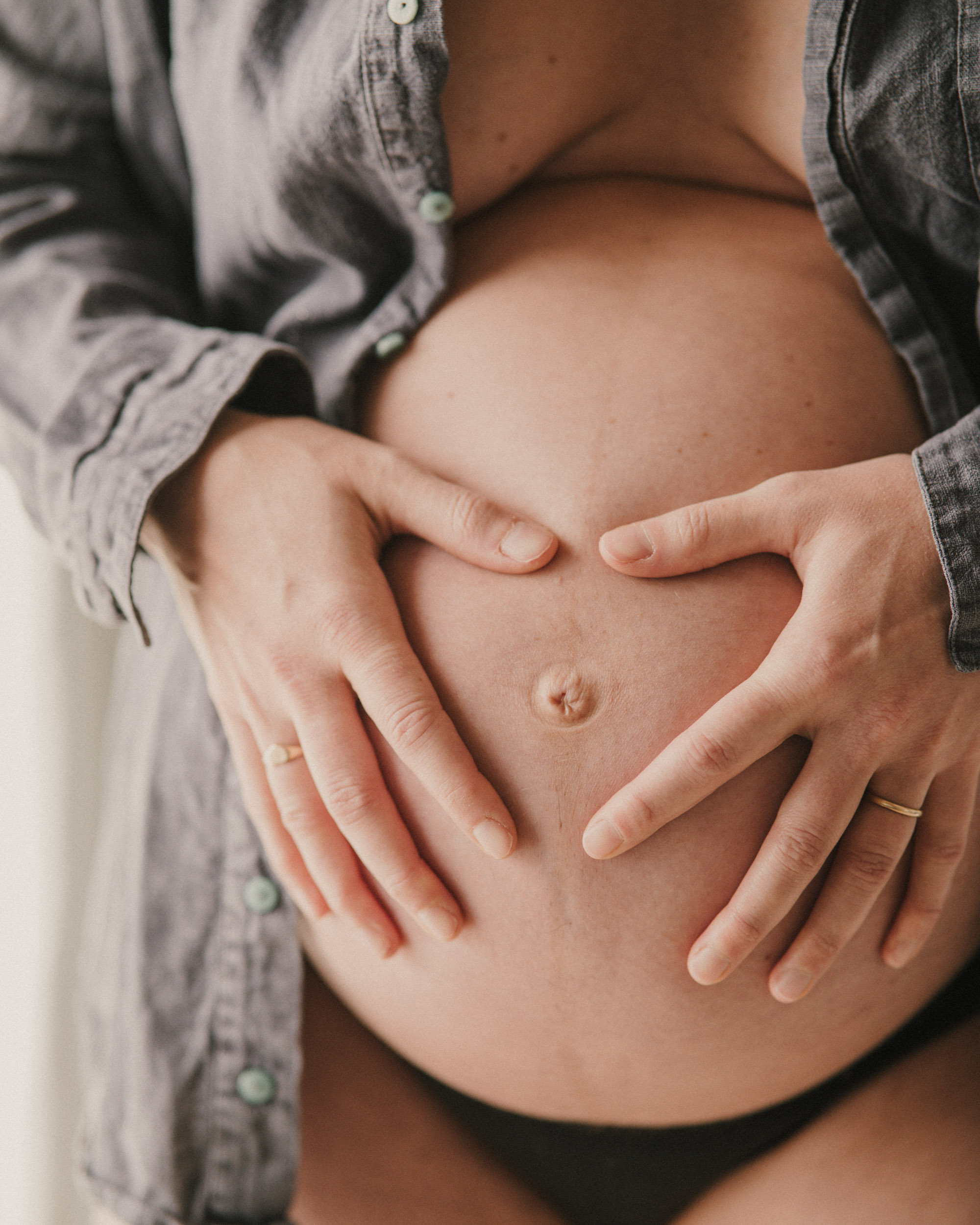 Women making love heart with hands on baby bump