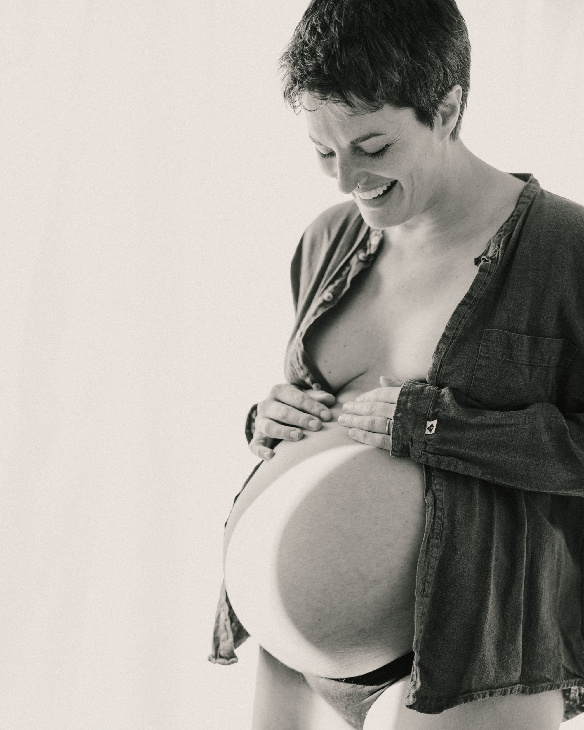 Women smiling holding baby bump