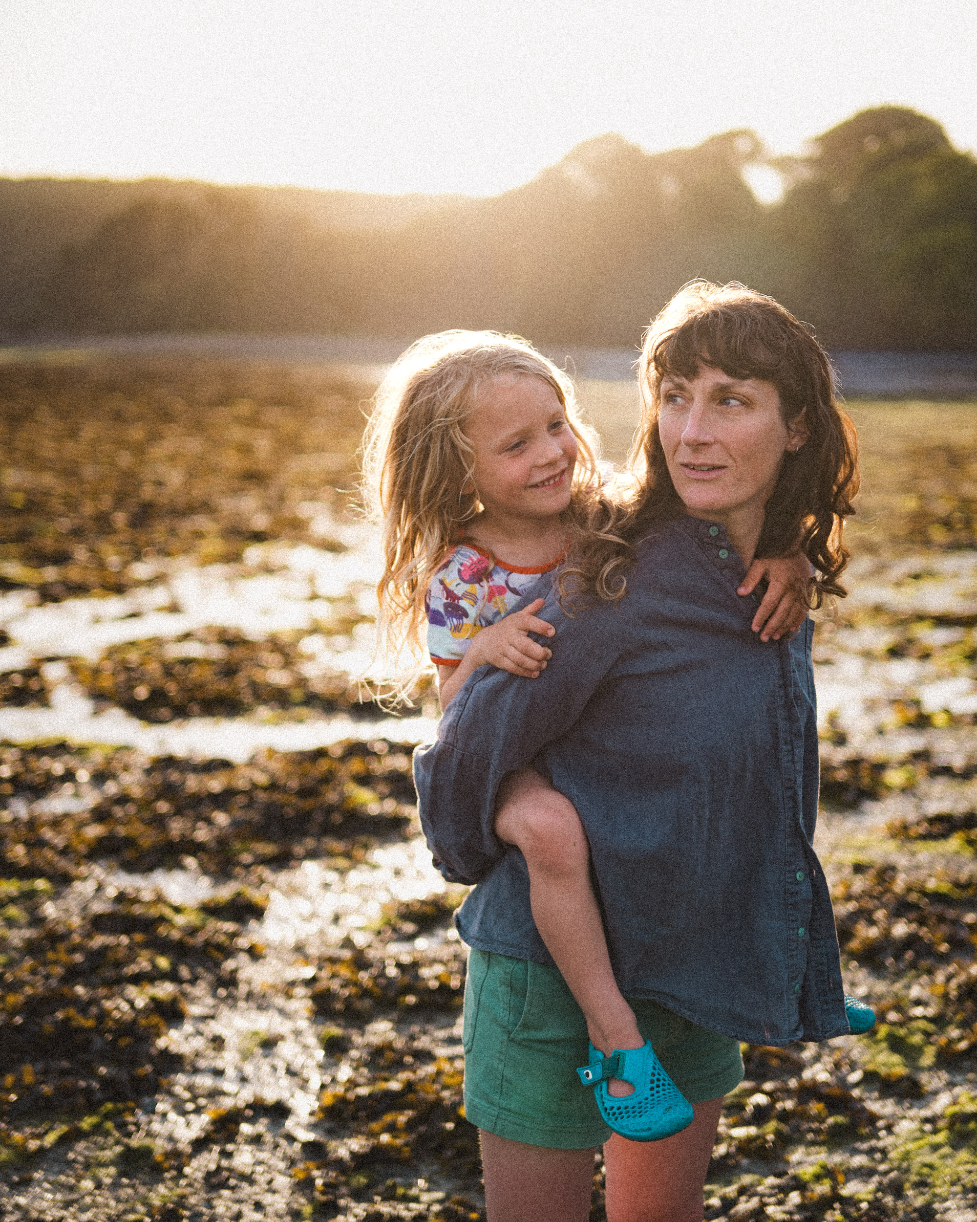 Picture of mother with son on her back, with the sun behind them in Cornwall