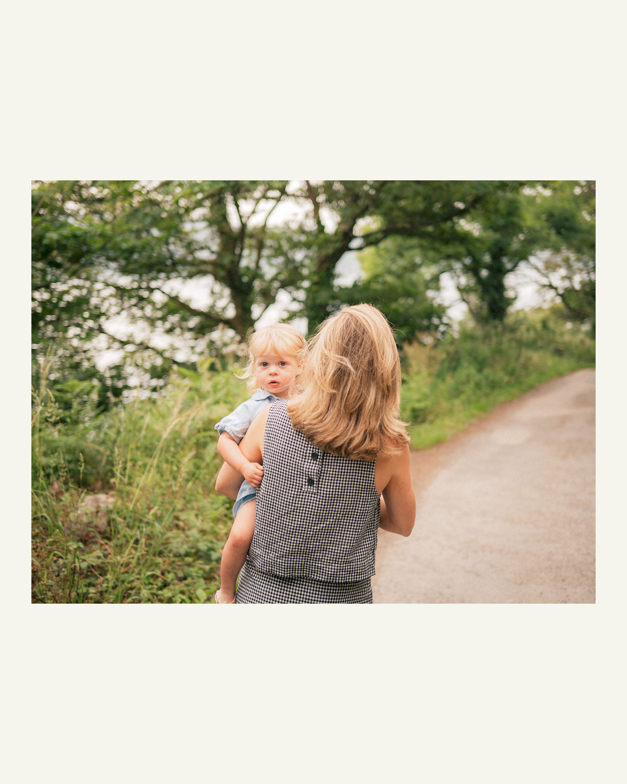 Mother carrying her young daughter along the wooded path between Grebe Beach and Durgan