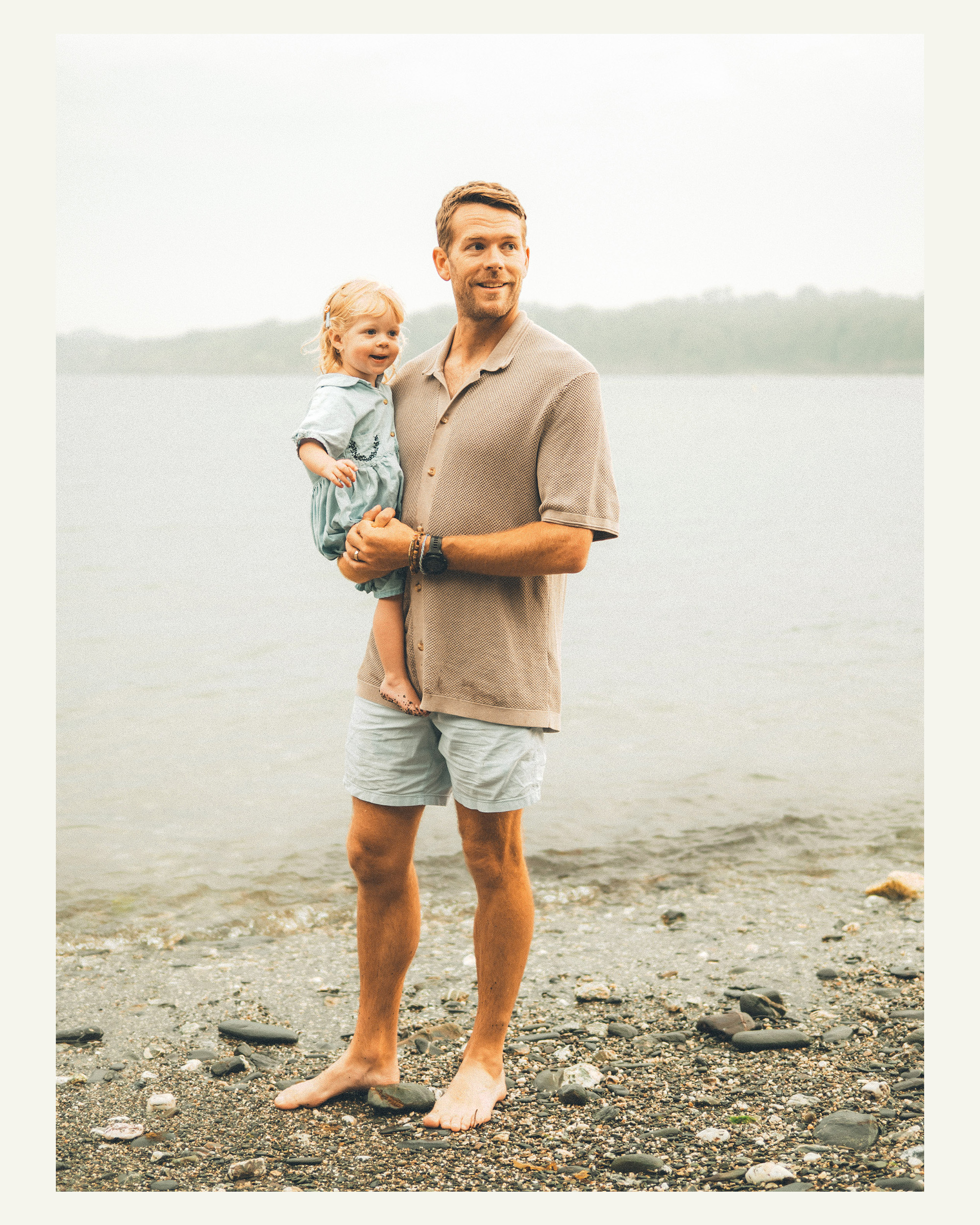Father holding his smiling young daughter beside the water at Grebe Beach near Falmouth