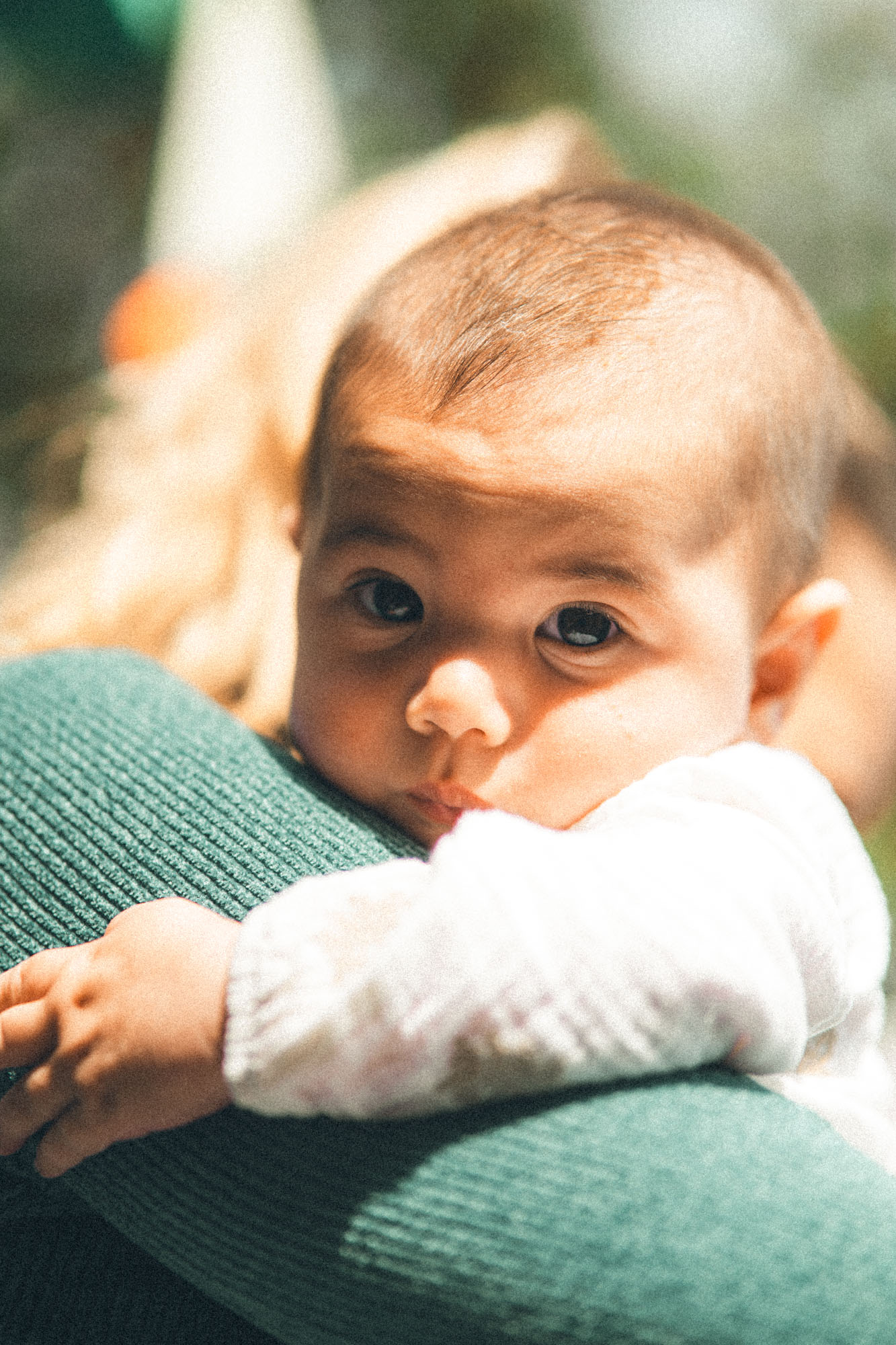 Close portrait of a baby resting over their mother's shoulder during an at-home family shoot