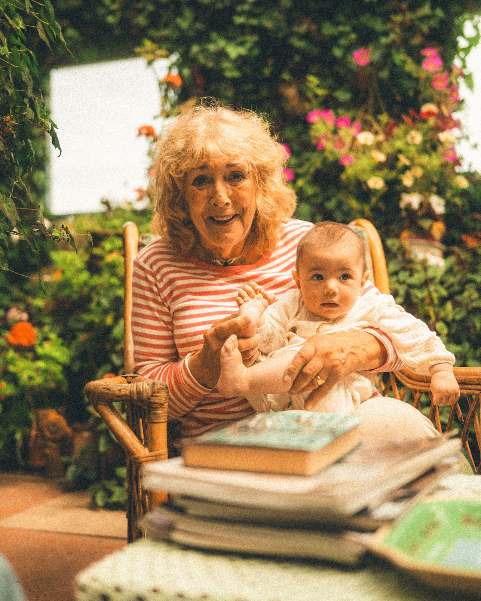Grandmother holding her baby grandchild in a flower-filled garden near St Ives
